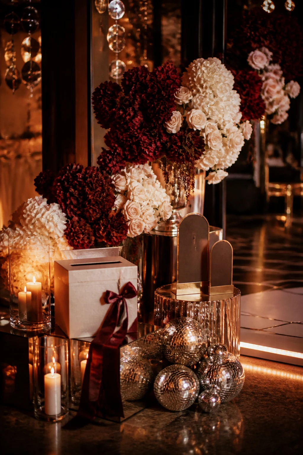 Celebration accessories styled with burgundy florals, candlelight, and mirrored details